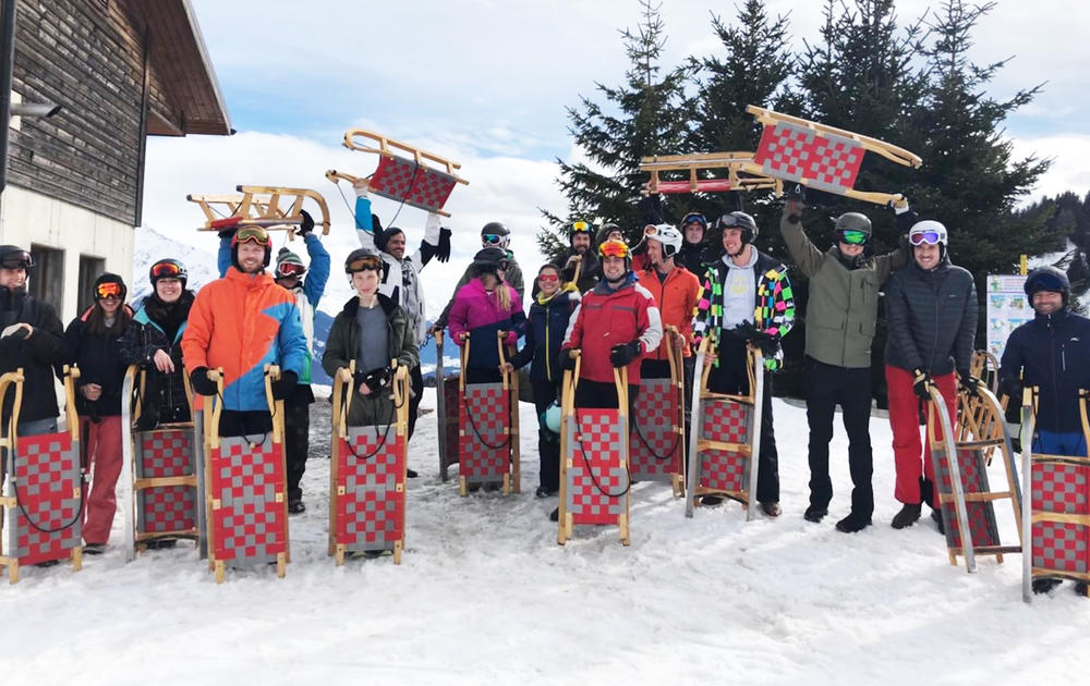 group photo of people with red and grey sledges in the snow